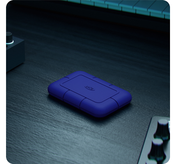 Blue LaCie Rugged SSD Pro5 sitting on black oak table top